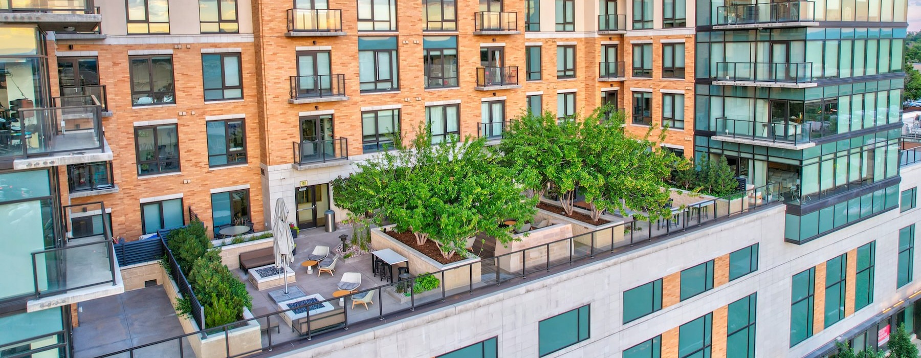 an aerial view of a rooftop terrace with trees, tables and chairs